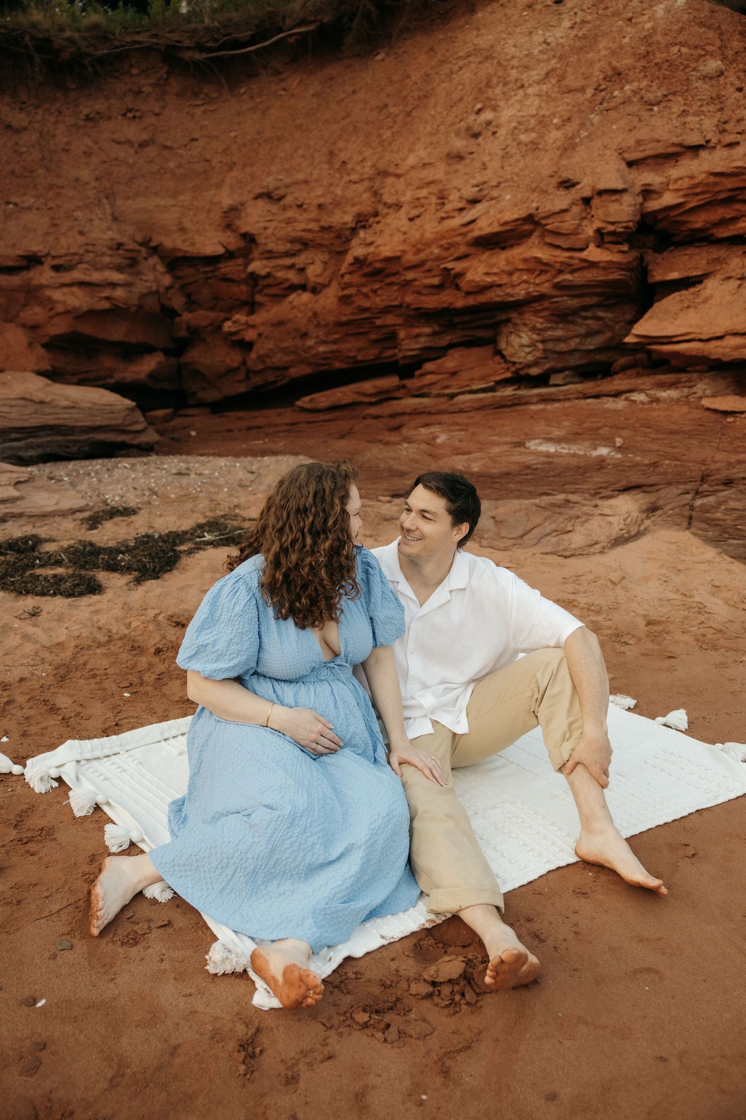 Romantic couple's photo session on a white blanket against red rock formations.