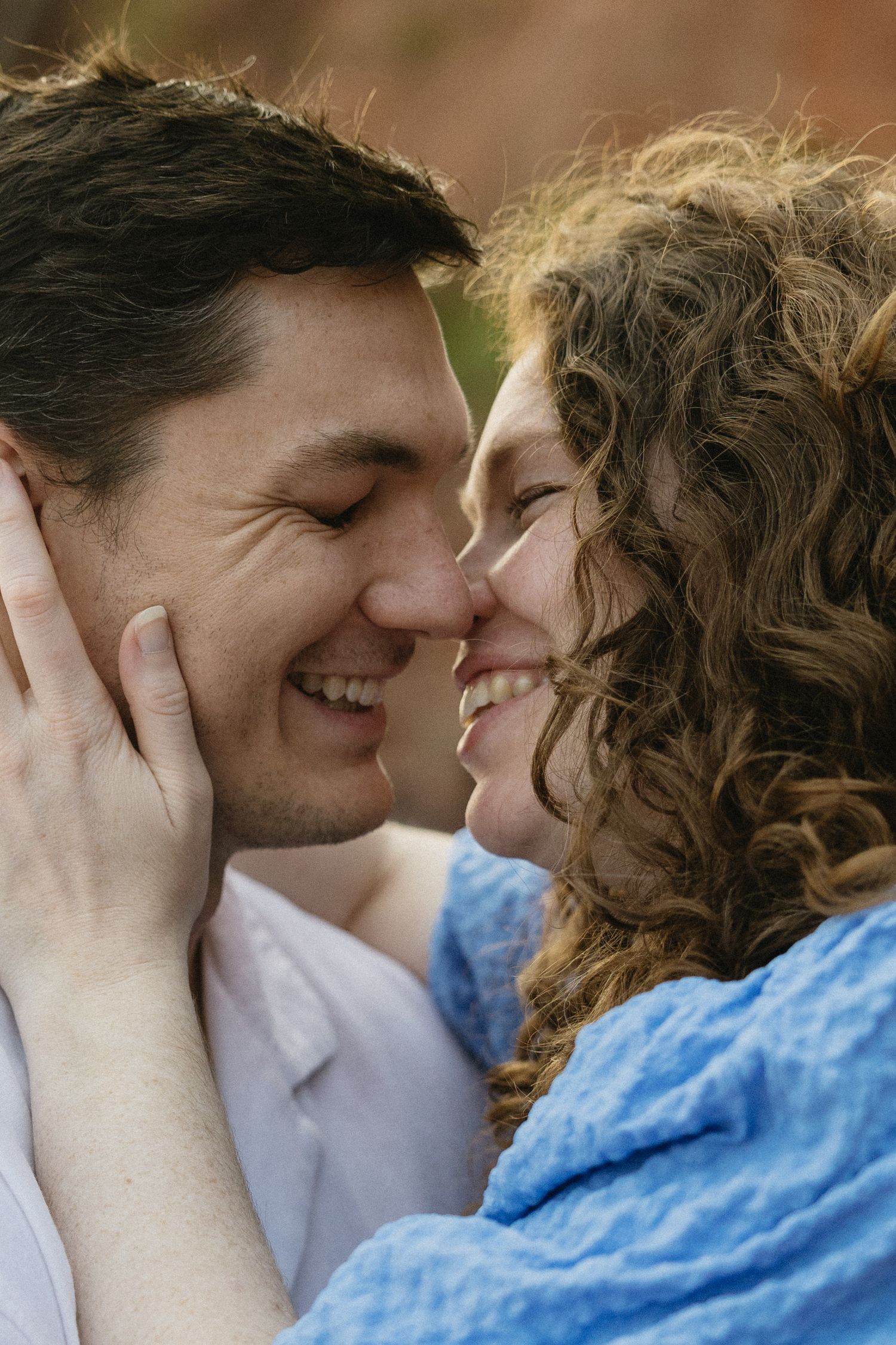 A couple shares an intimate close-up moment together outdoors.