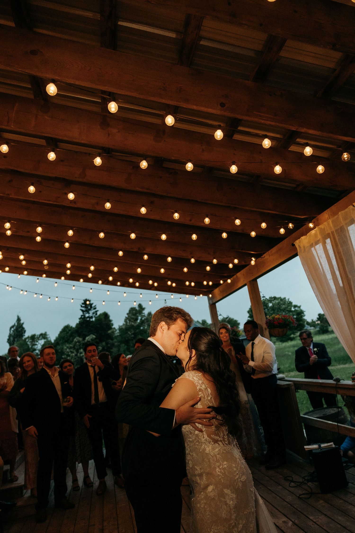 Romantic dance under string lights on an outdoor deck at dusk.
