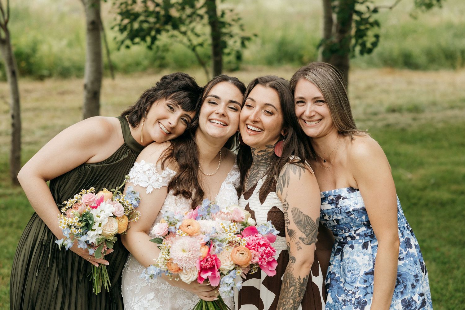Wedding party members holding colorful bouquets while posing outdoors.