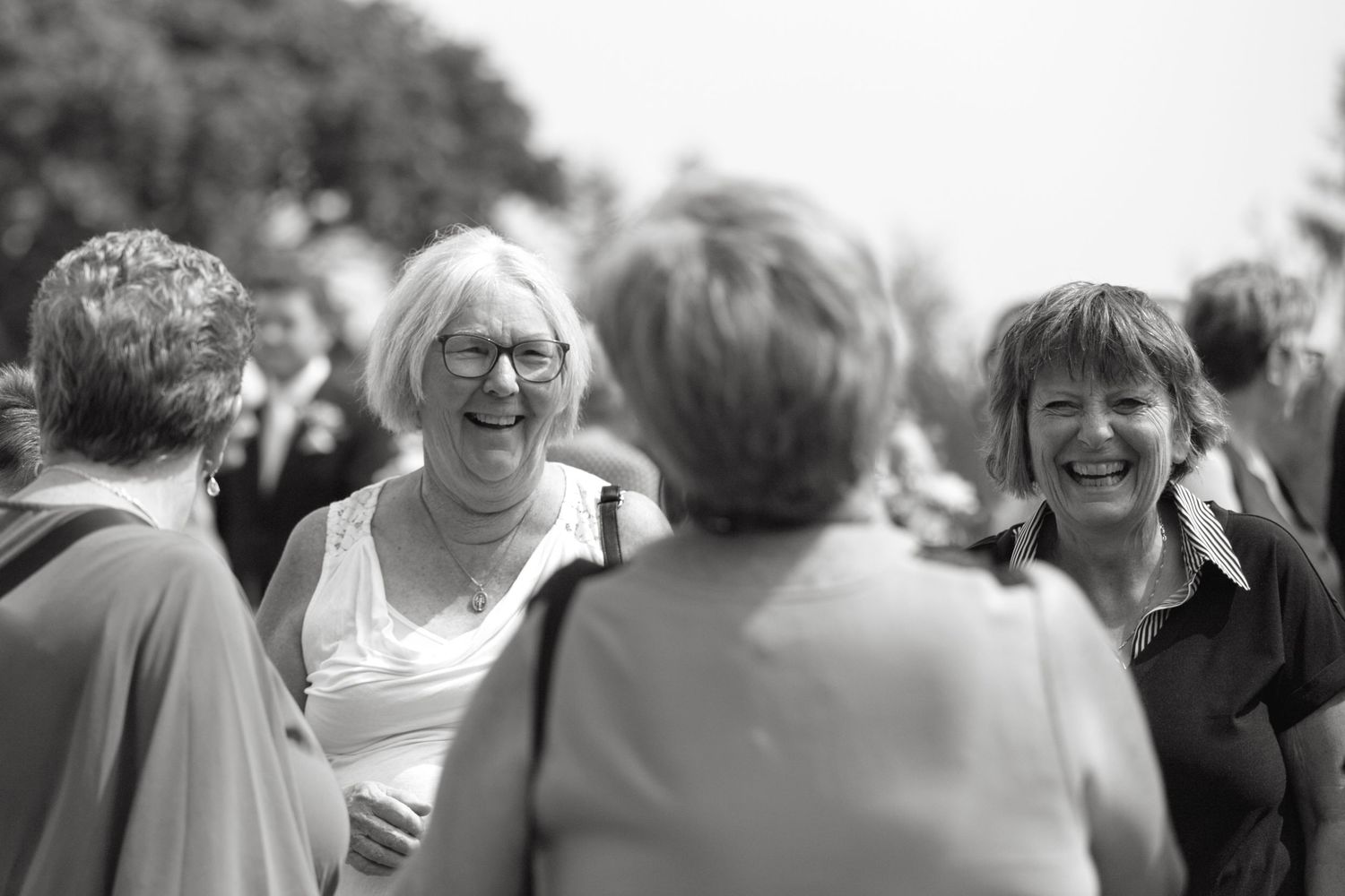 Black and white candid shots of wedding guests sharing joyful moments.