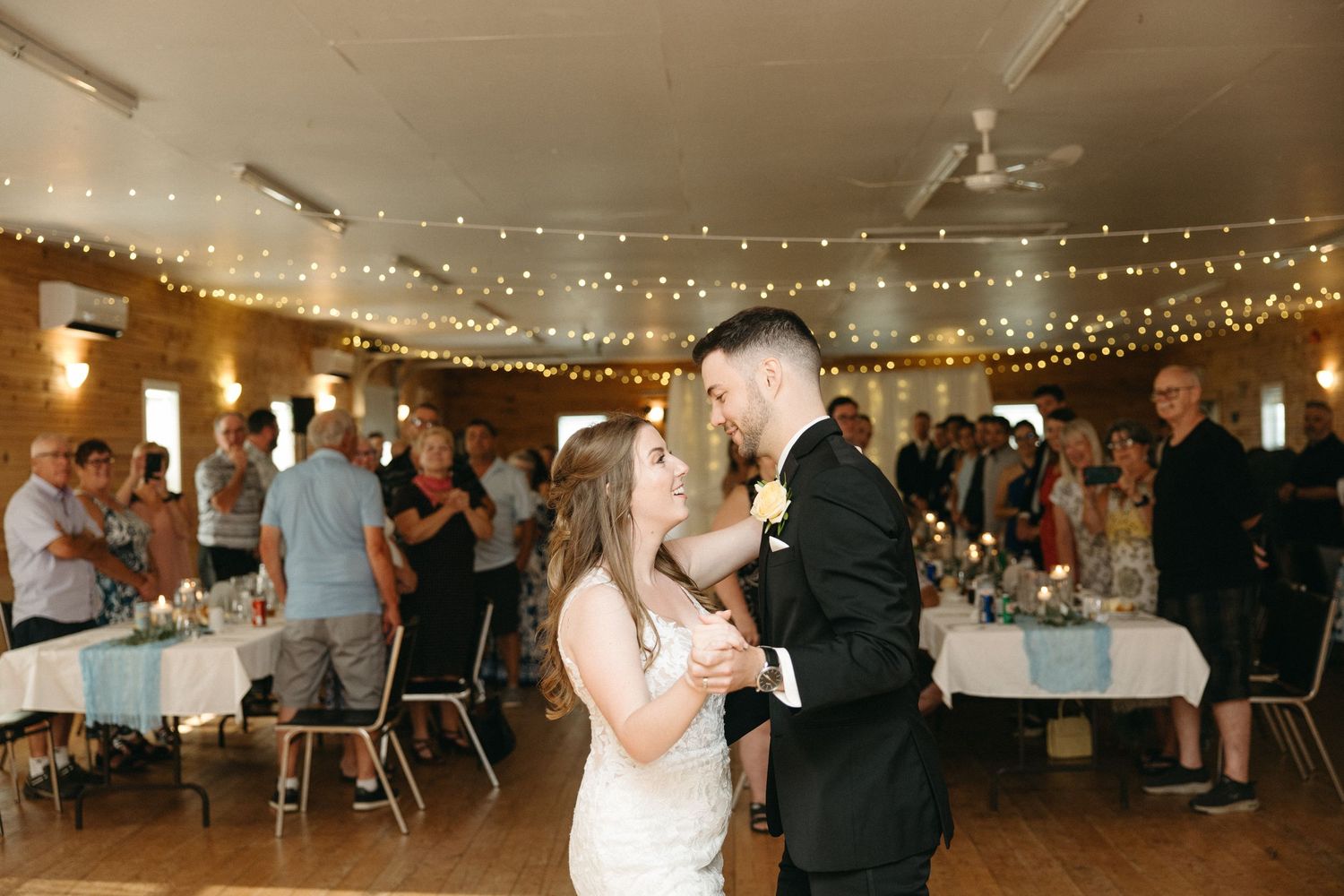 Wedding reception hall decorated with string lights and white drapery.