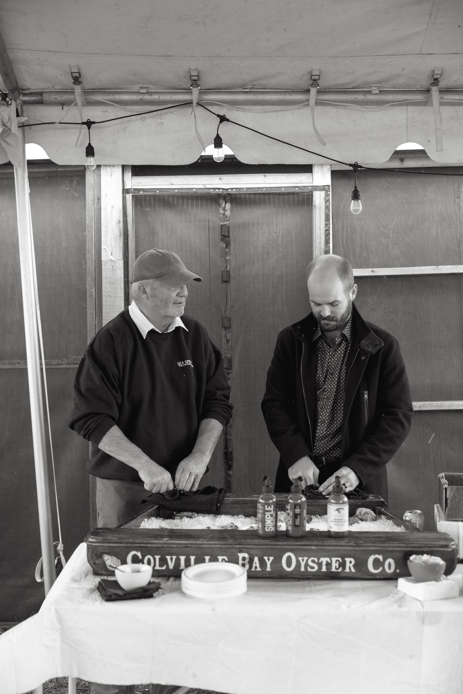 Oyster shucking station under a white tent with staff preparing fresh seafood.