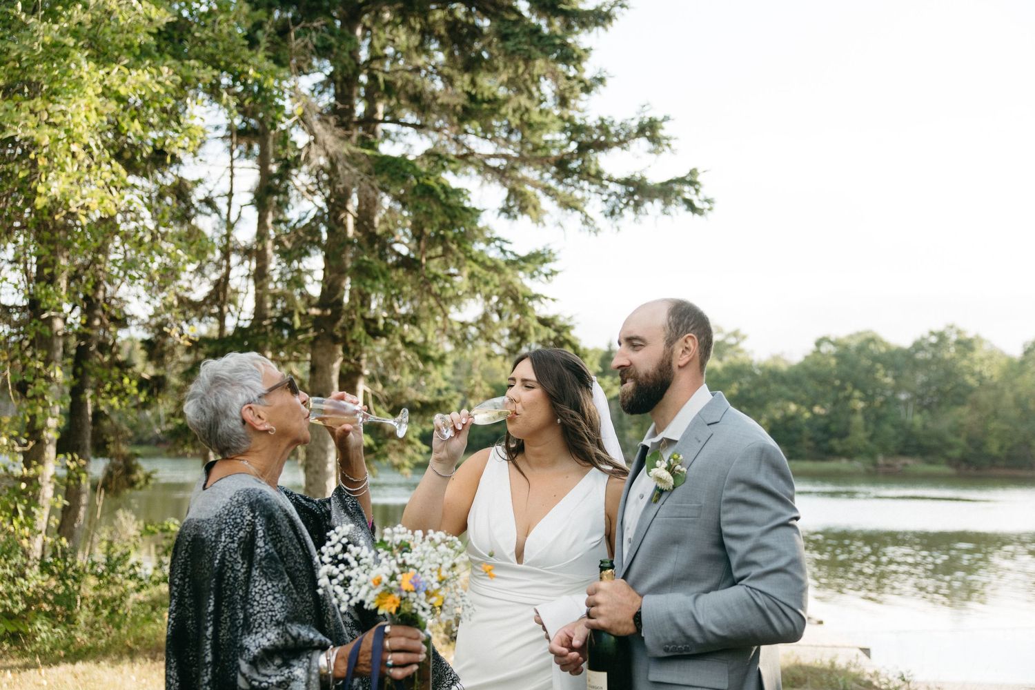 Wedding celebration on waterfront with champagne toasts at sunset.