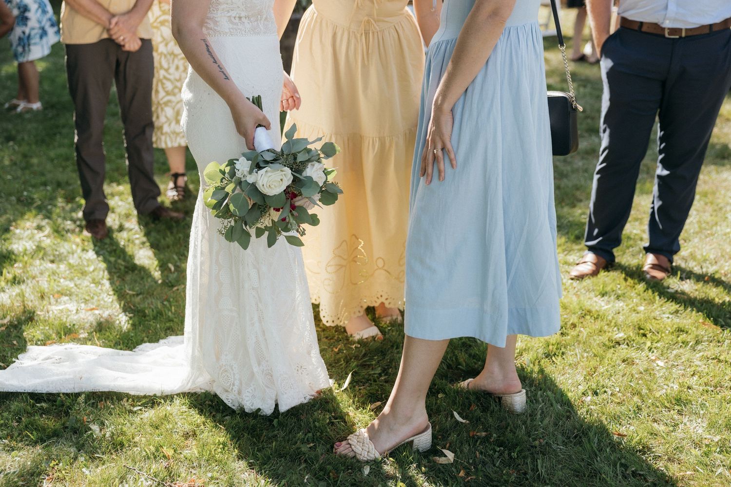 Wedding party members in light colored dresses standing together outdoors.