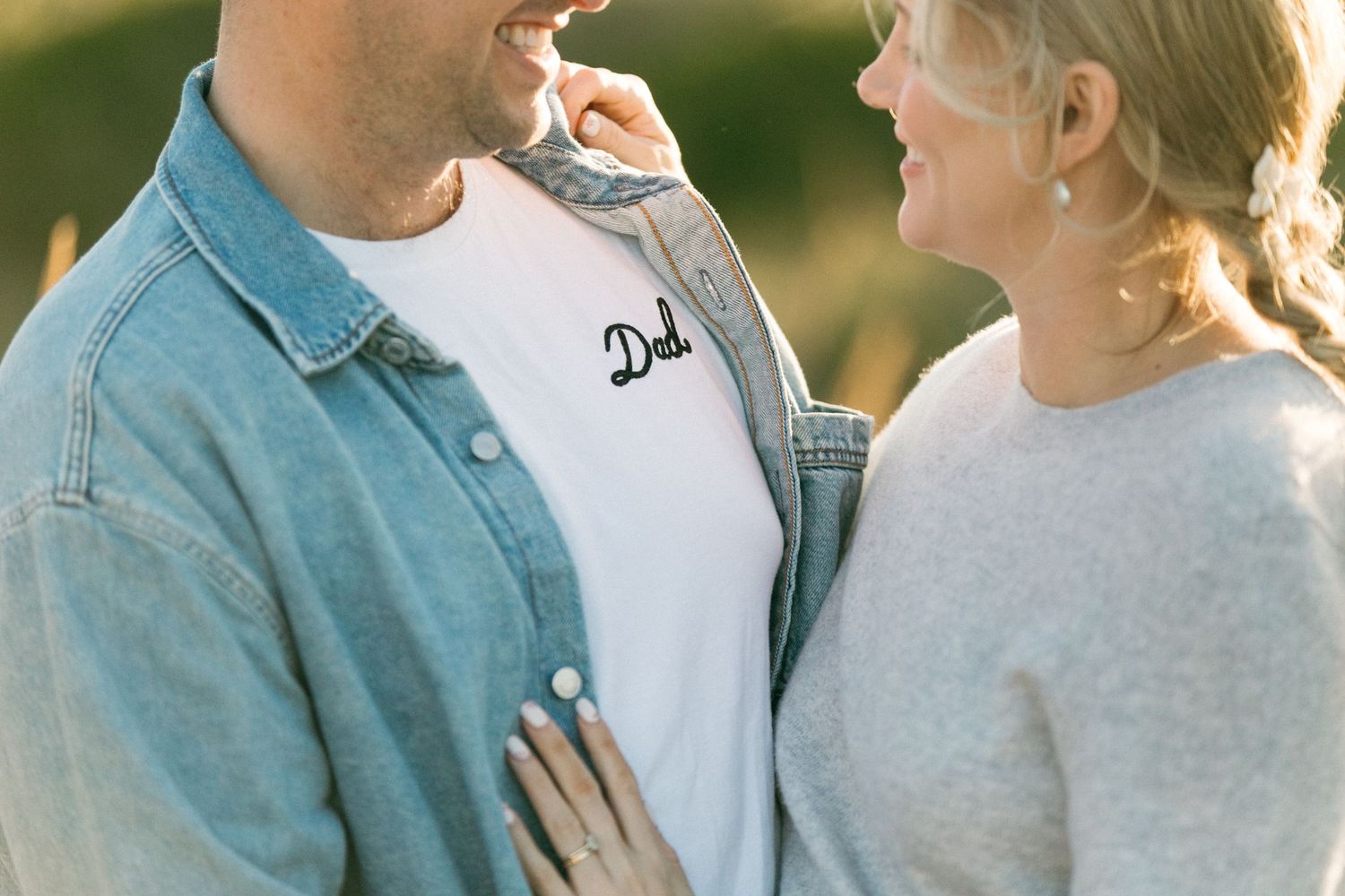 A tender moment shared between two people in casual denim and sweaters outdoors.