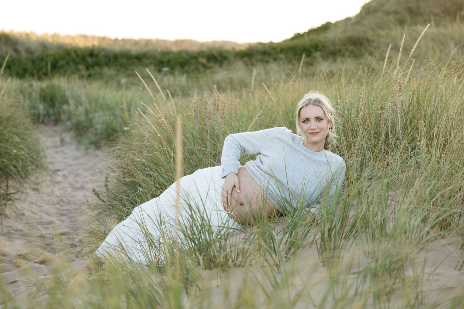 Grassy sand dunes line a beach path at sunset.