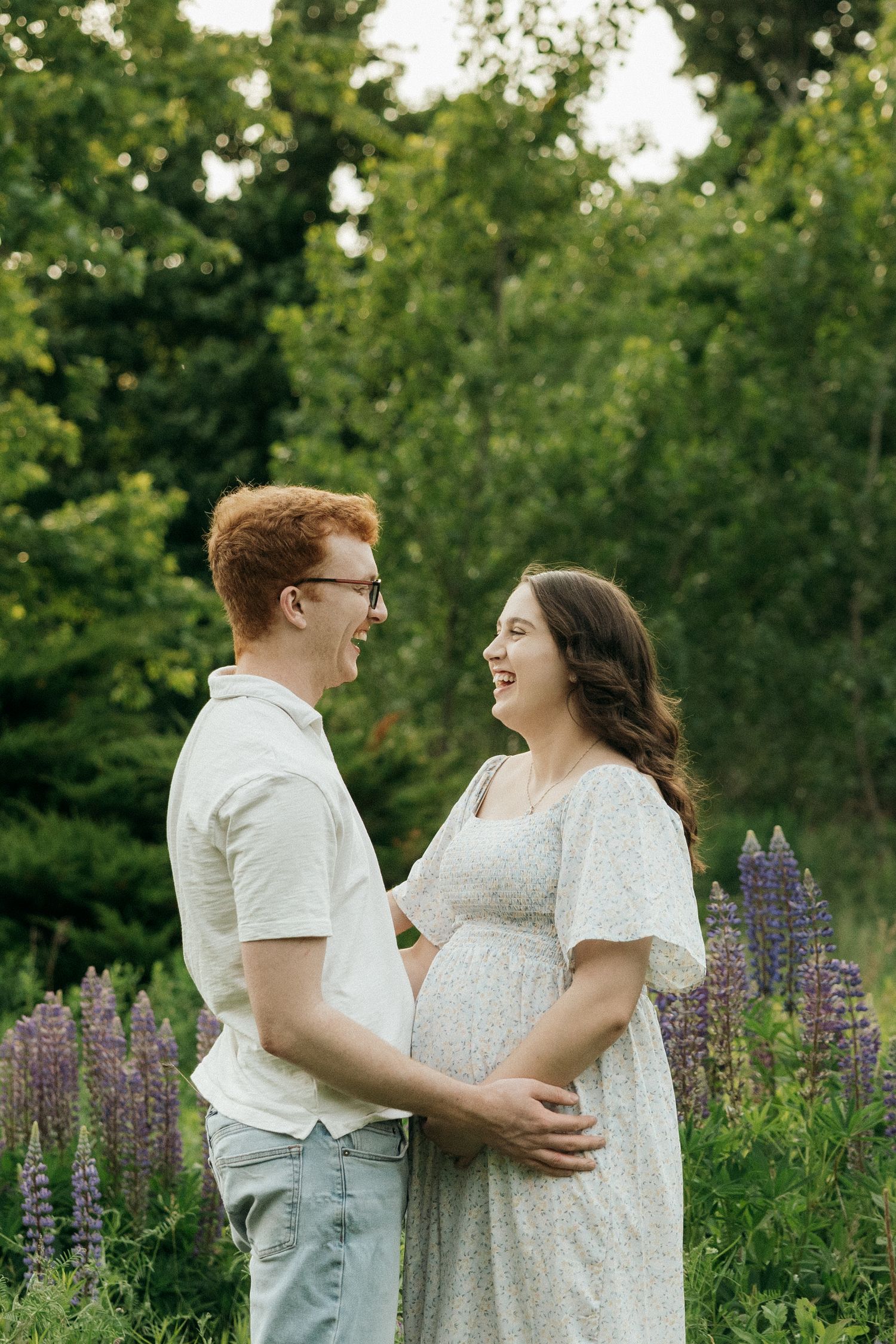 Couple sharing a joyful moment together among purple lupine flowers in a garden setting.