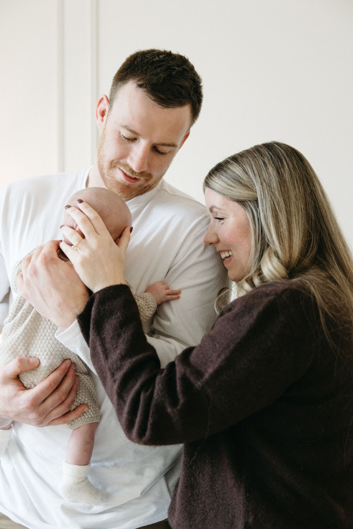 An intimate family moment captured in a bright, modern nursery setting with minimal decor.