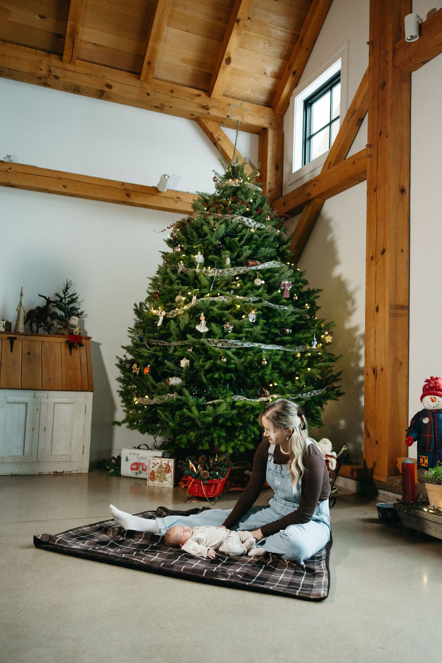 Wide view of family relaxing on blanket in rustic room with Christmas decorations.