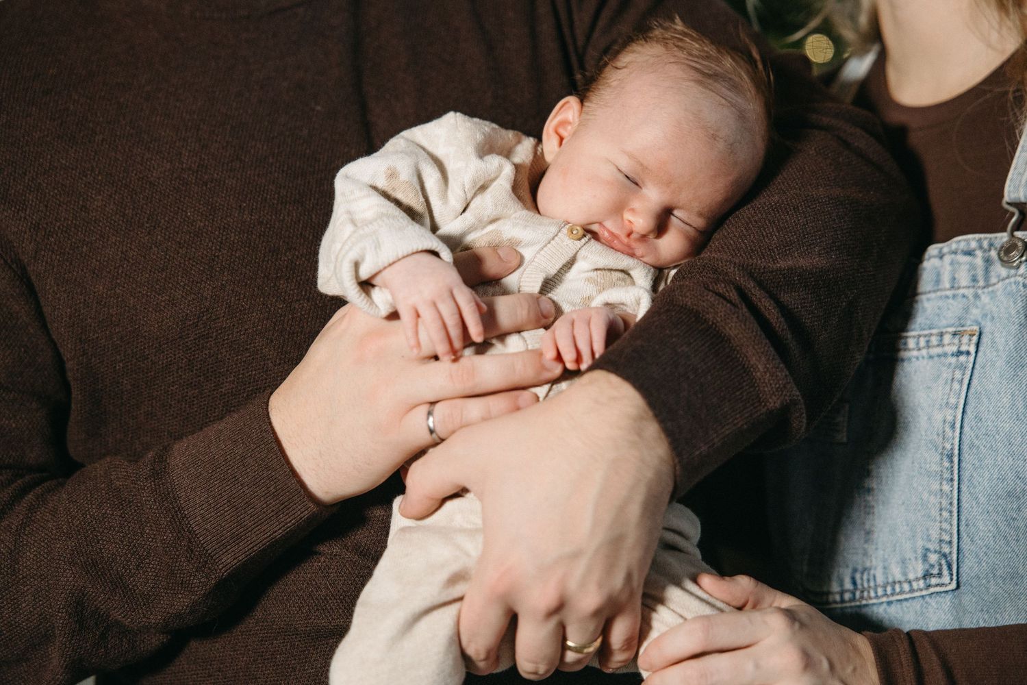 Intimate family photos showing loving interactions with an infant near Christmas decor.