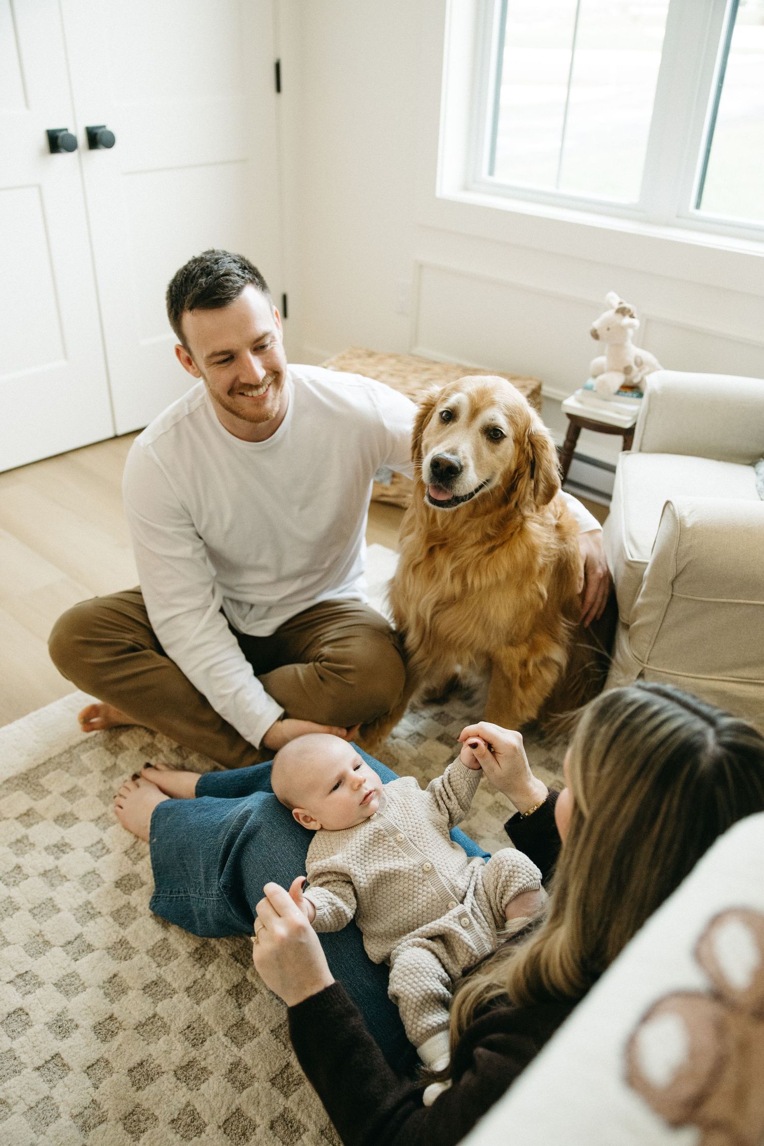 Golden retriever joins family for cuddle time on living room floor.