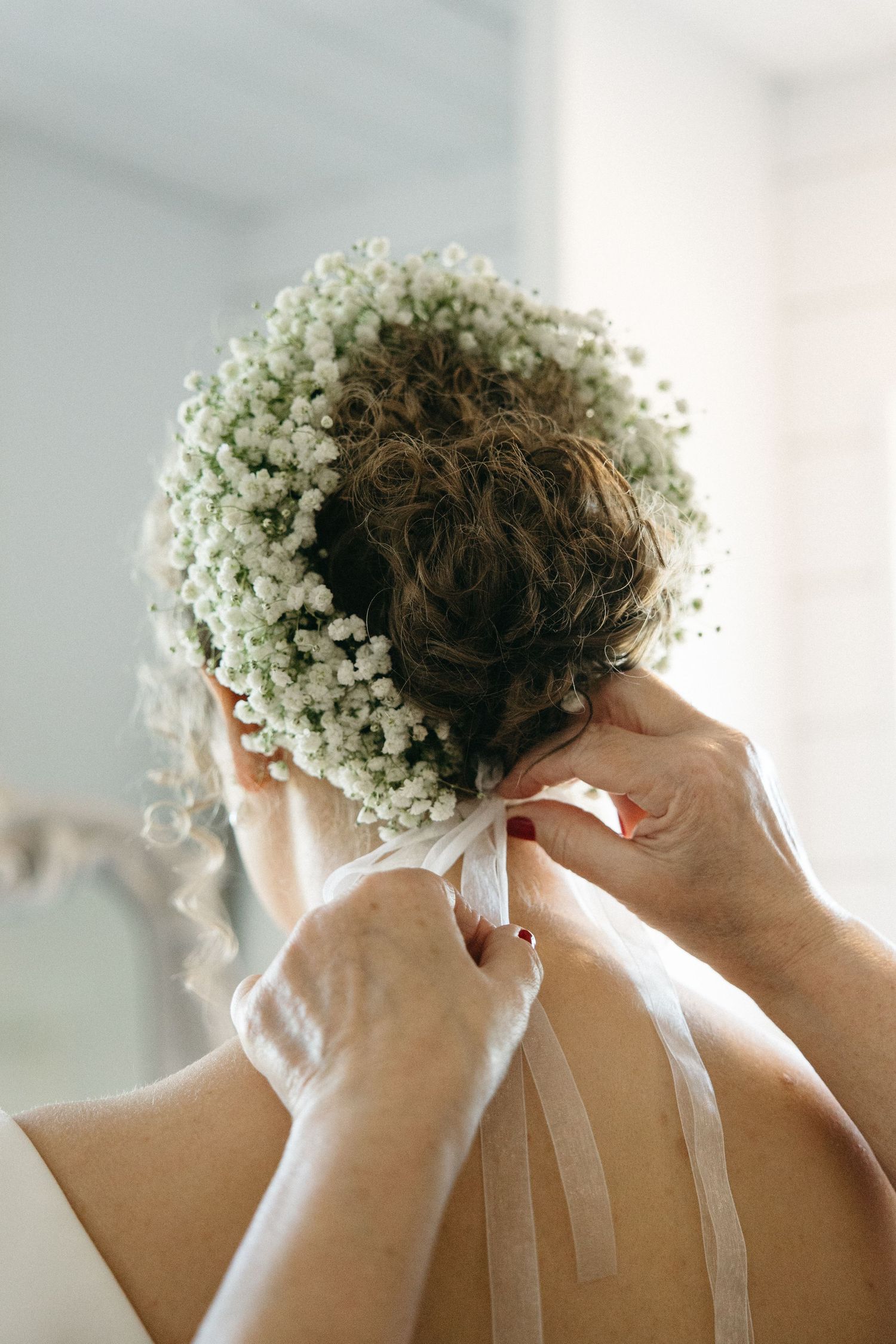Close-up of baby's breath flowers being arranged in a bridal hairstyle.