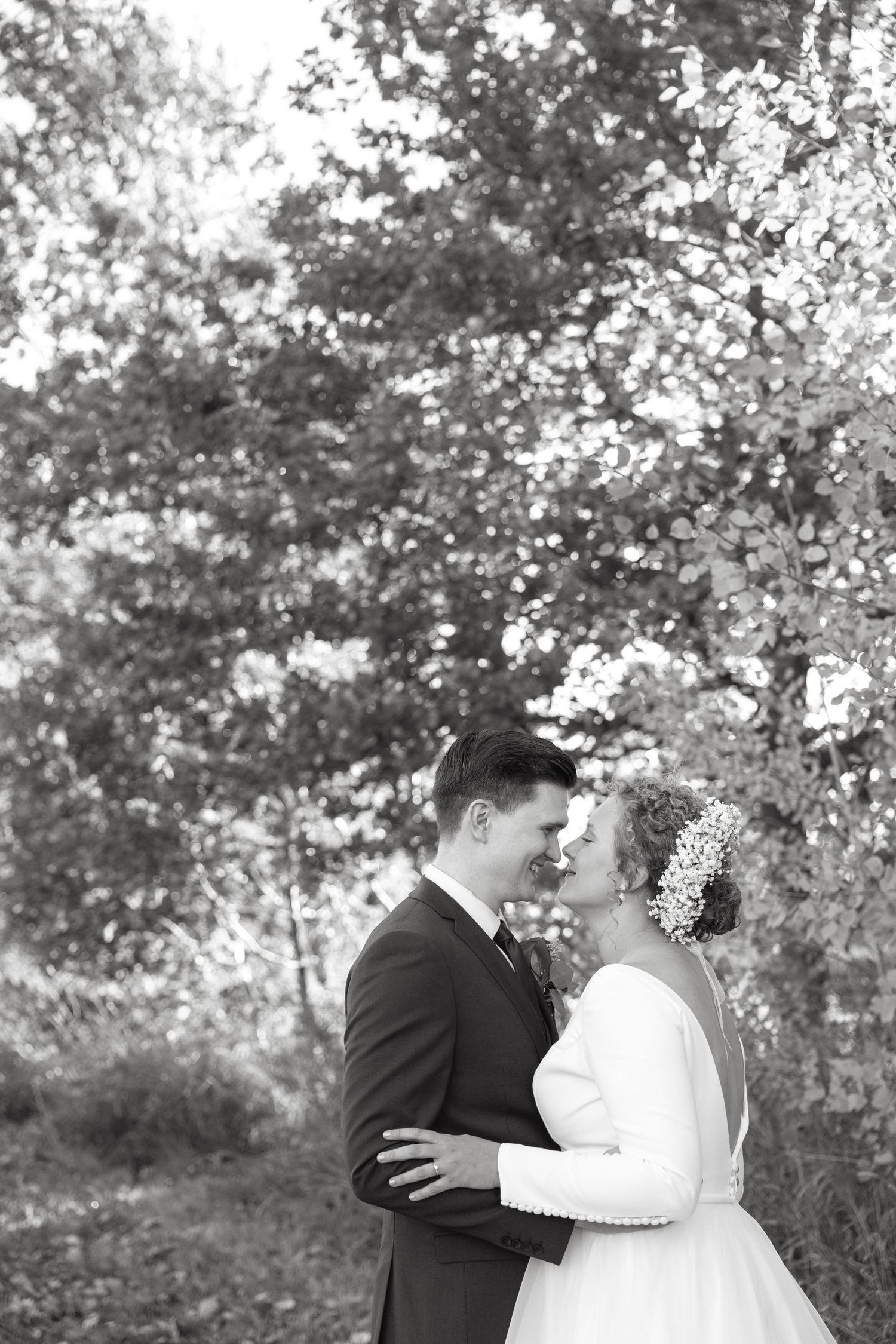 Black and white wedding portraits showing tender moments between couple in outdoor setting.