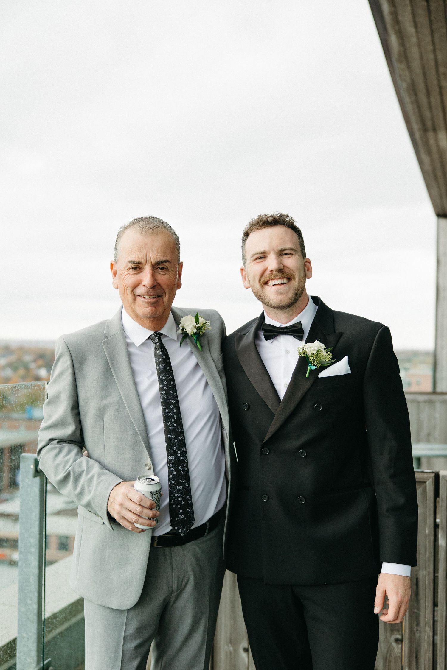 Two guests in formal attire share a drink on an outdoor terrace.