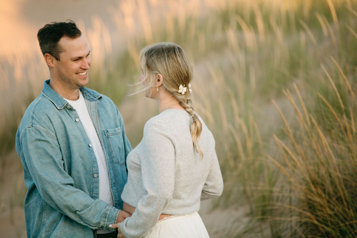 Couple sharing an intimate moment in tall grass during golden hour.