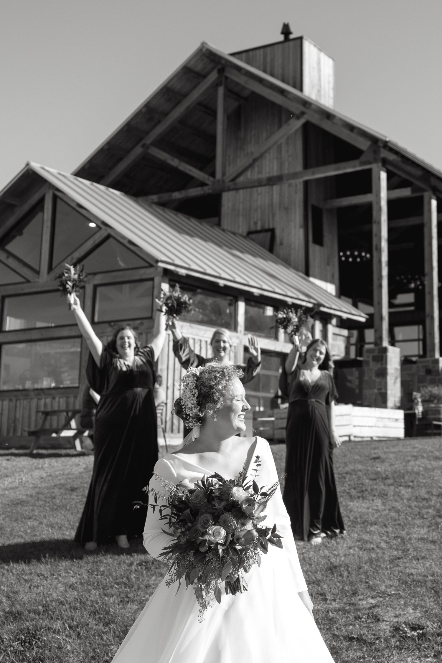 Wedding party posing for photos outside a rustic barn venue.