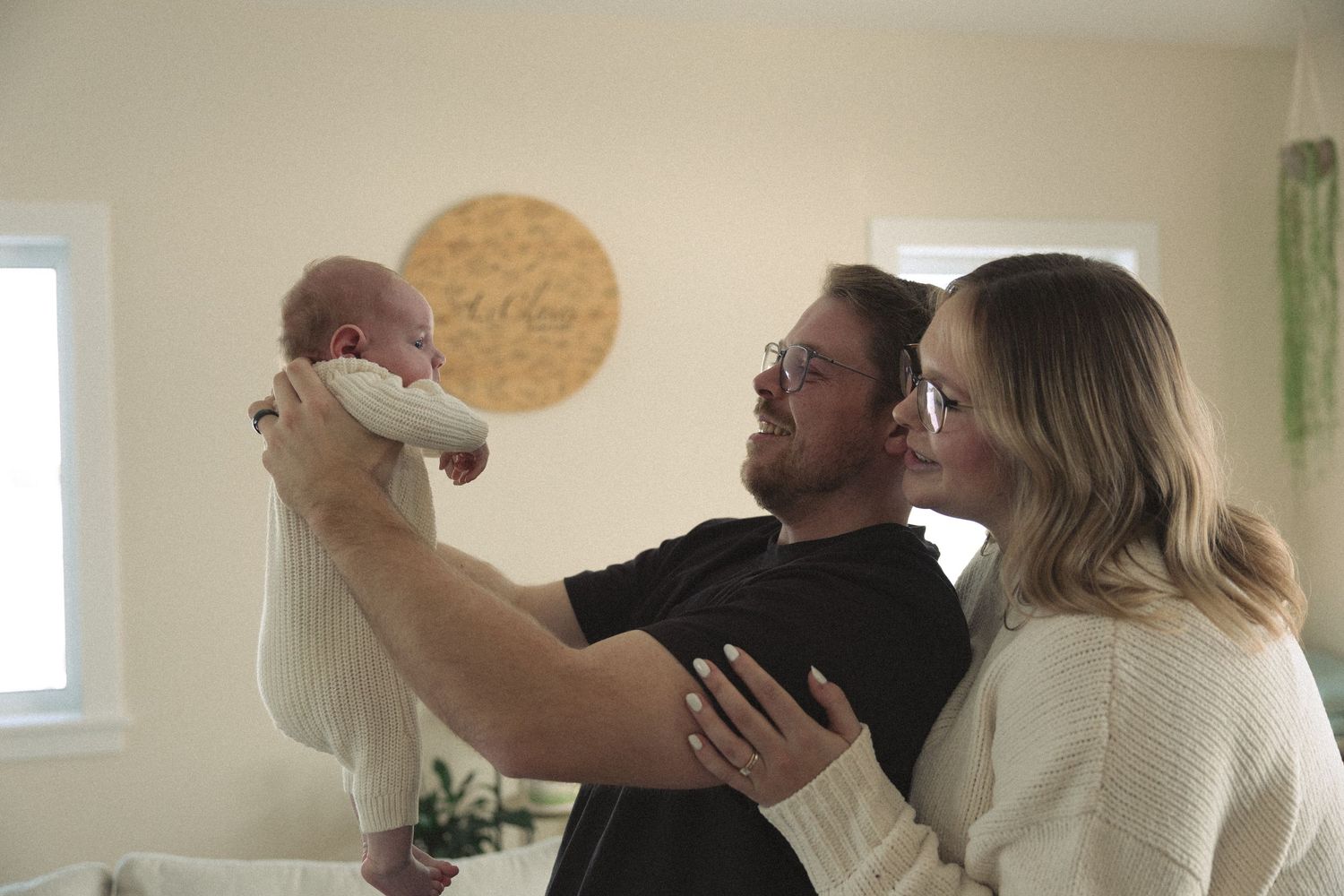 A couple shares a tender moment in a bright room while holding a framed photo.