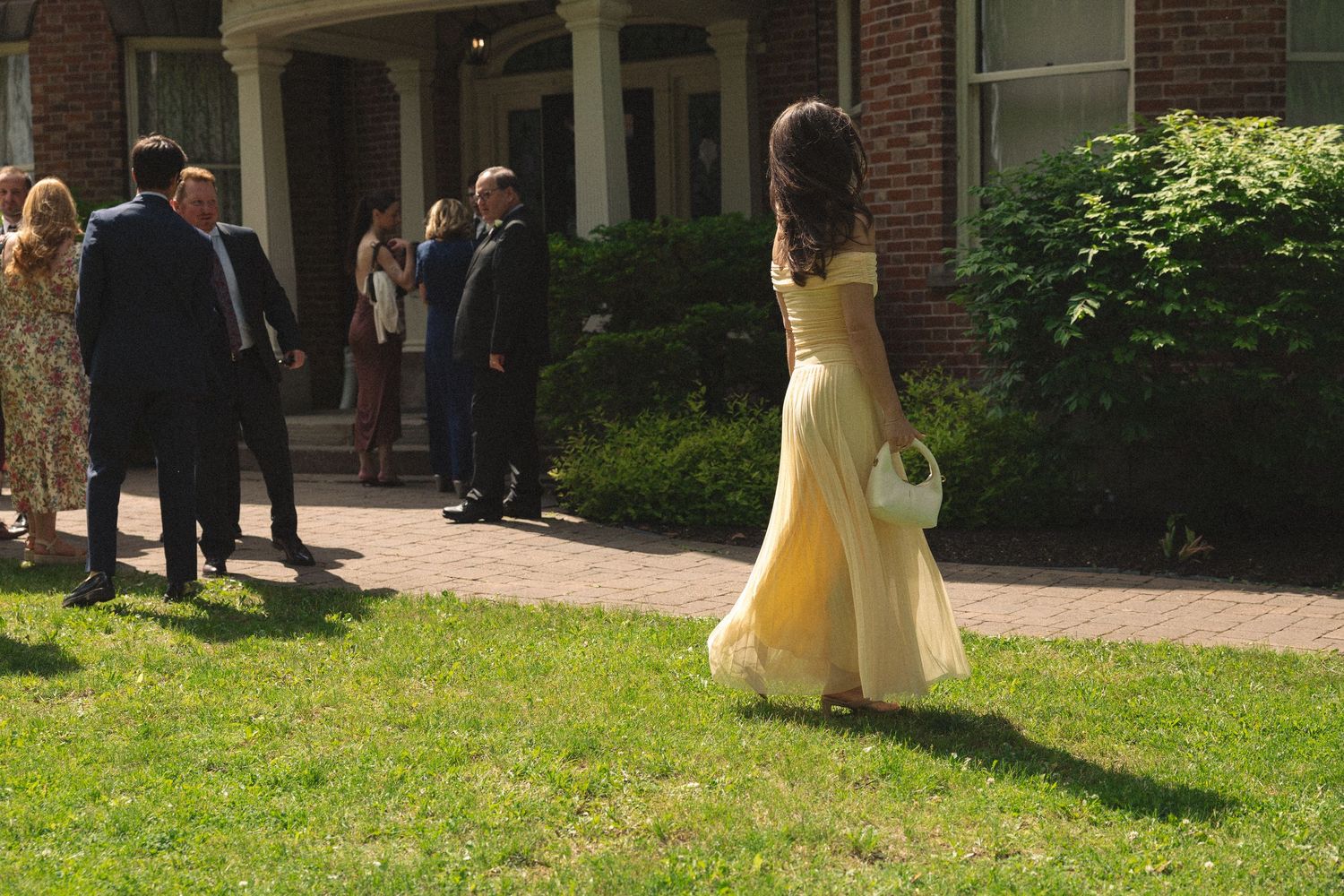 Wedding ceremony setup outside a historic brick building with guests gathered on the lawn.