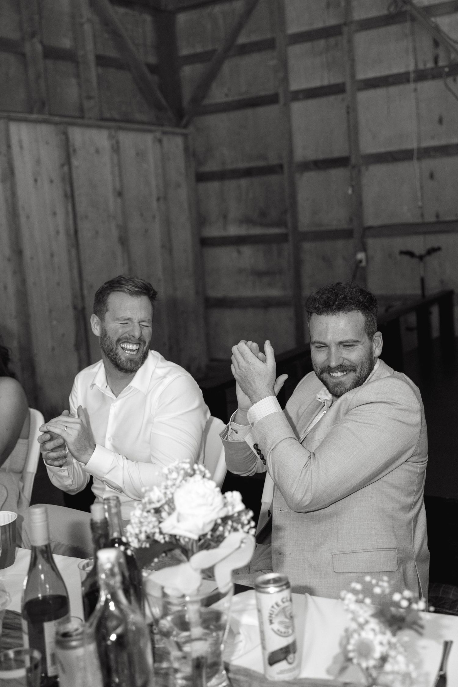 Two guests sharing a joyful moment at a wedding reception table.