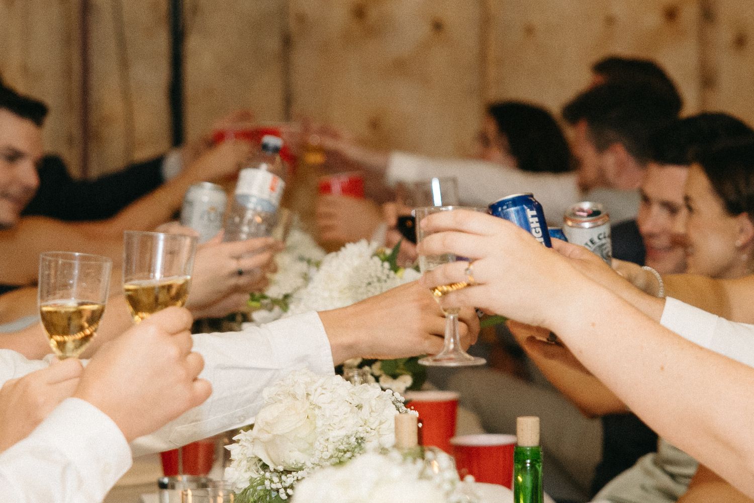 Wedding guests raise glasses for a toast during barn reception celebration.