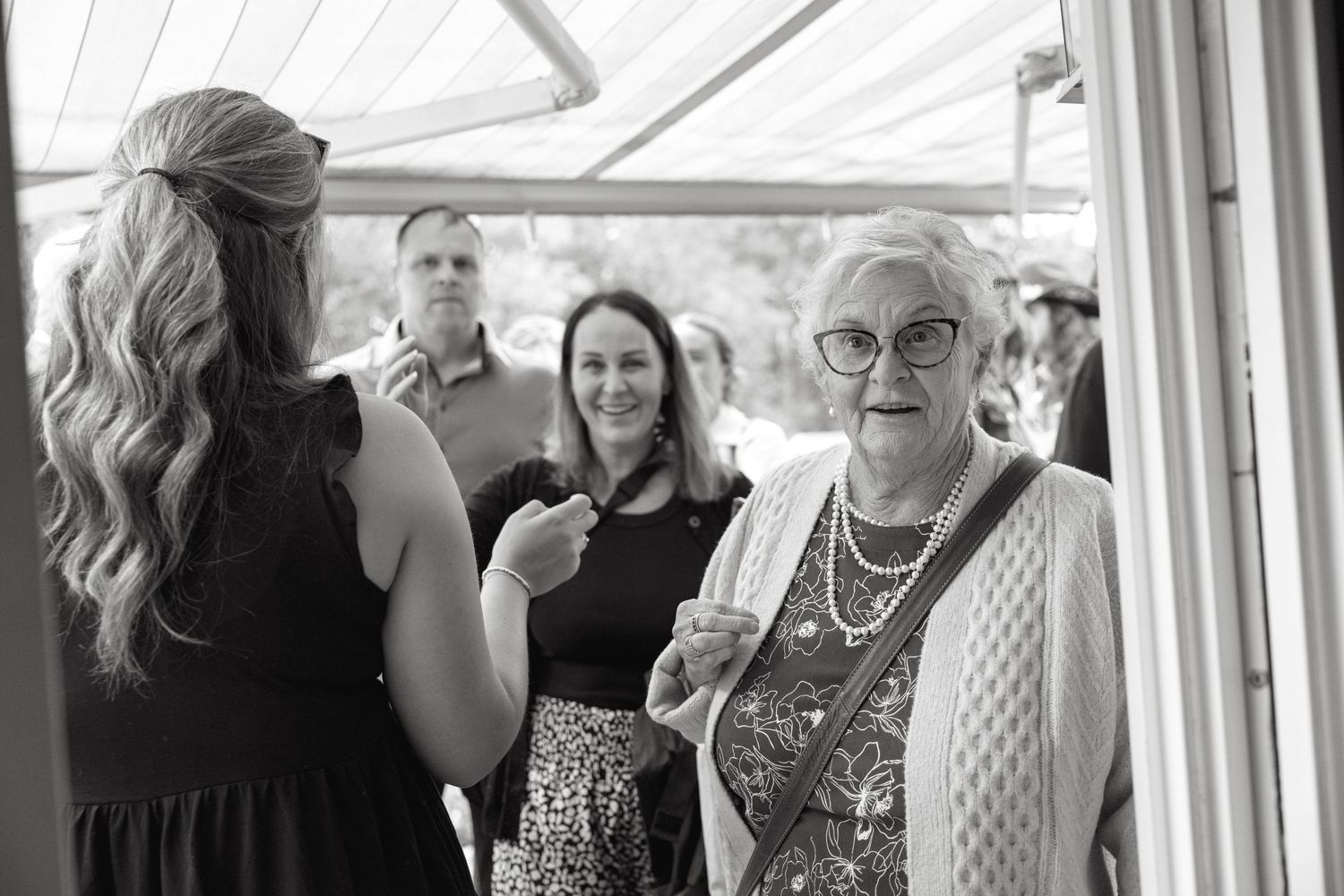 Black and white photo of wedding guests socializing during an indoor reception.