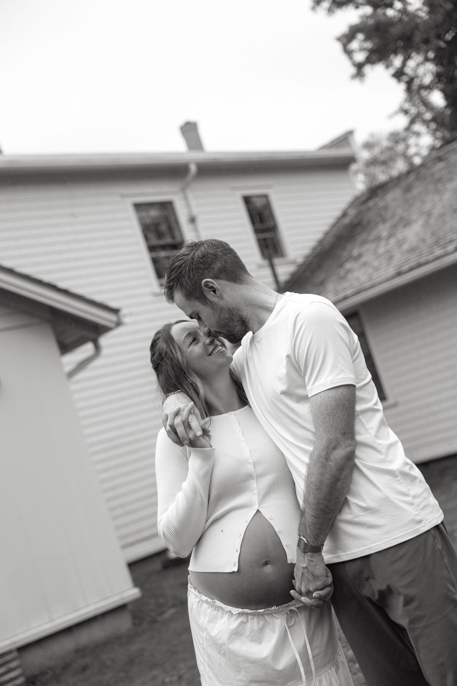 Black and white maternity photo of a couple kissing while the man holds the pregnant woman's belly.