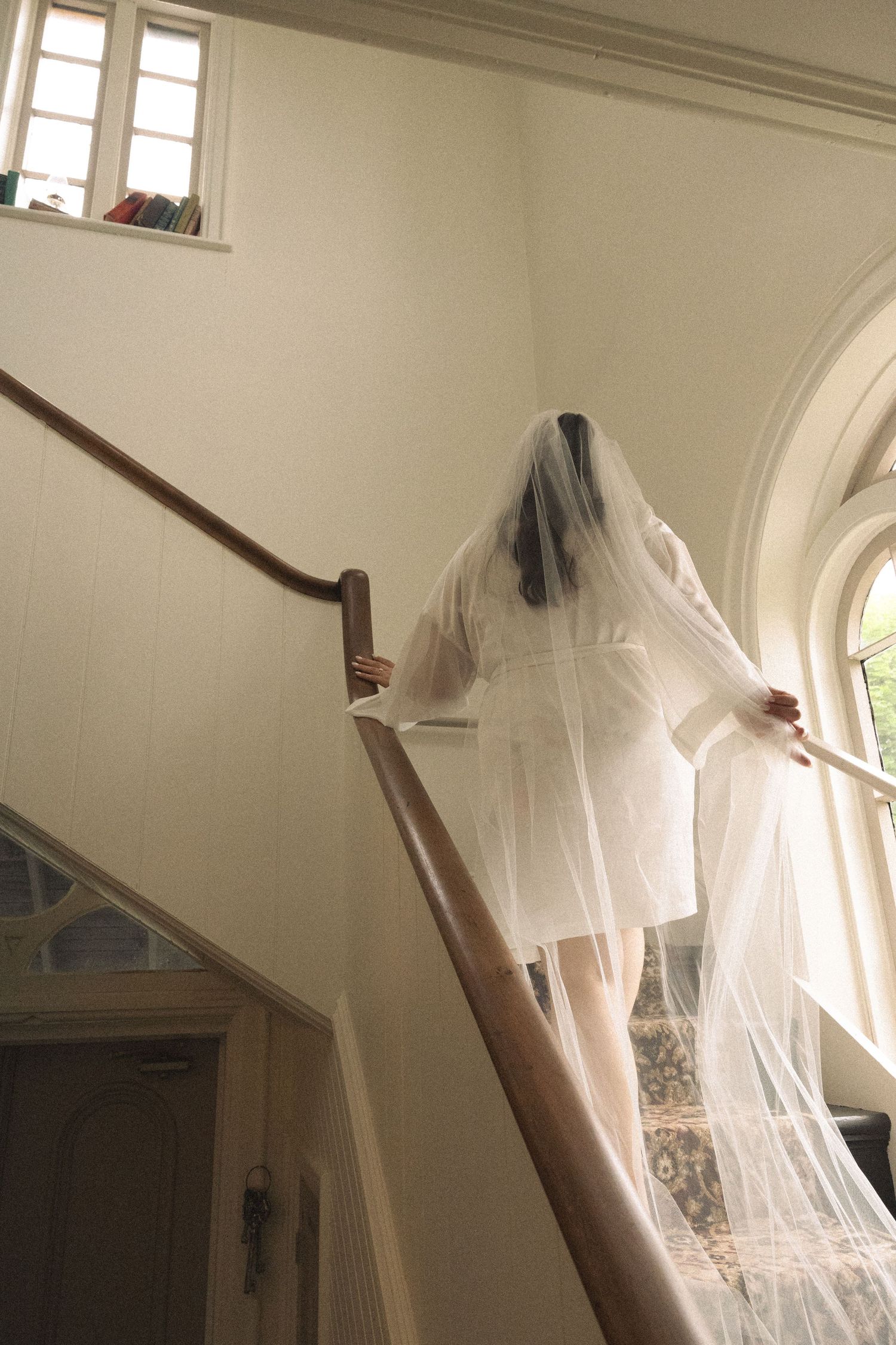 White wedding dress hanging in a room with arched windows and natural light.