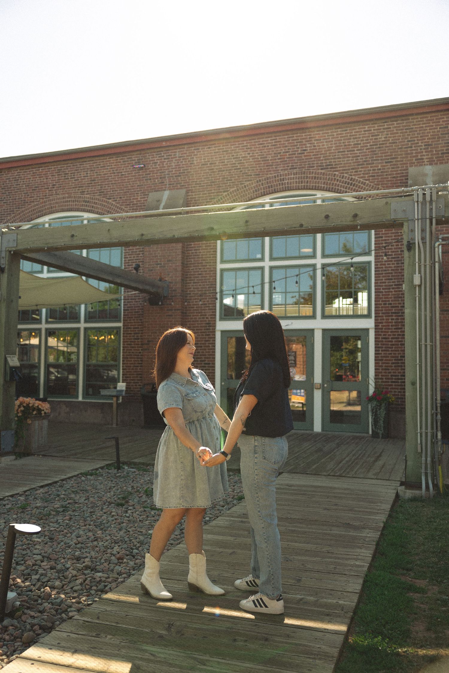 Two people walking and interacting playfully on wooden steps outside a brick building.