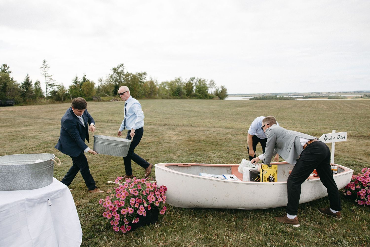 Group setting up decorations along a grassy outdoor venue with pink flowers.