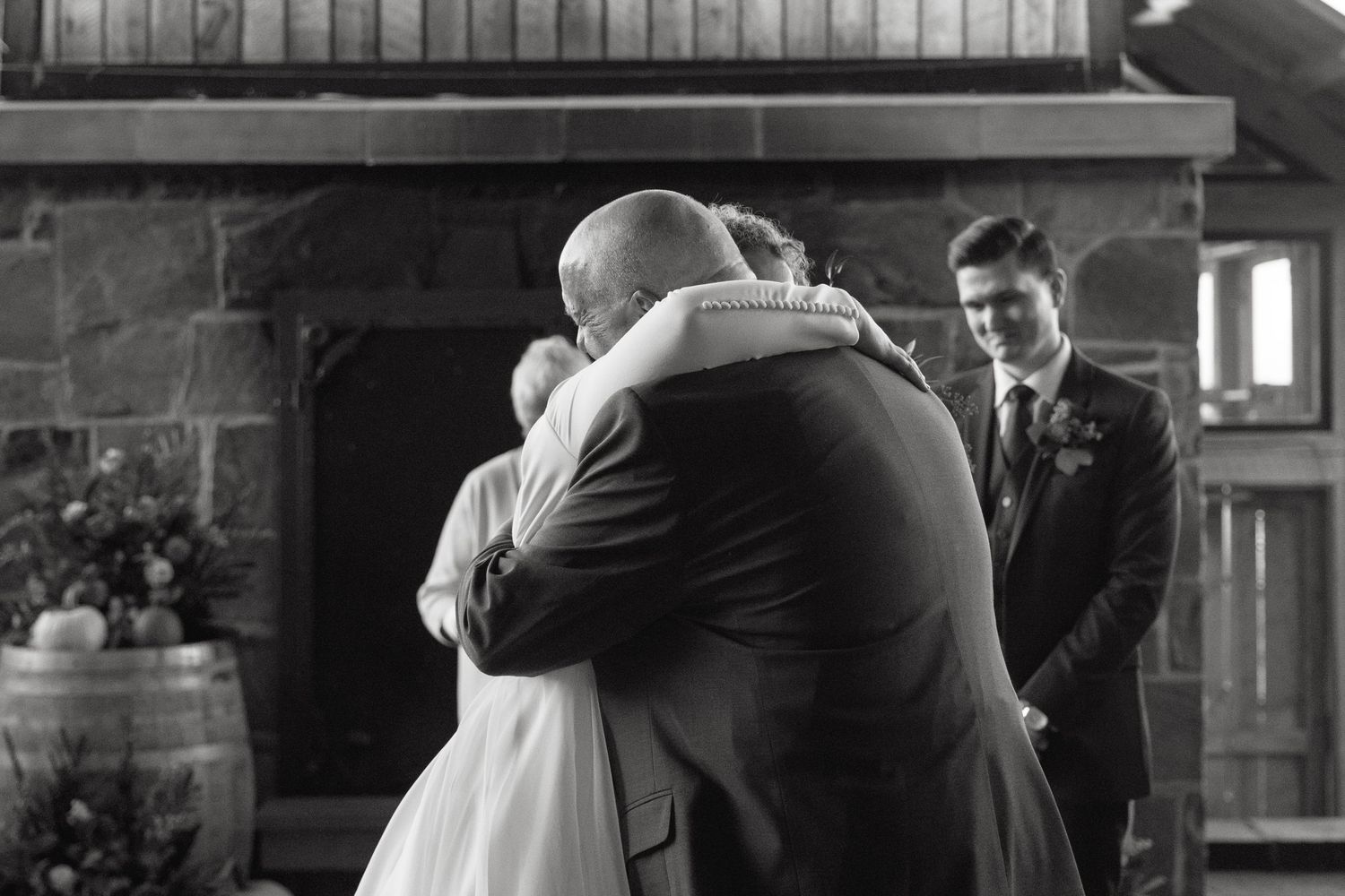 Emotional wedding ceremony moment captured in a rustic venue with stone fireplace.