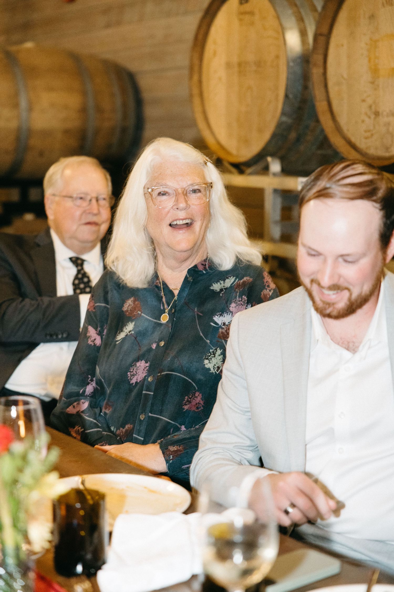Wedding reception dinner in a wine cellar with guests seated at long tables.