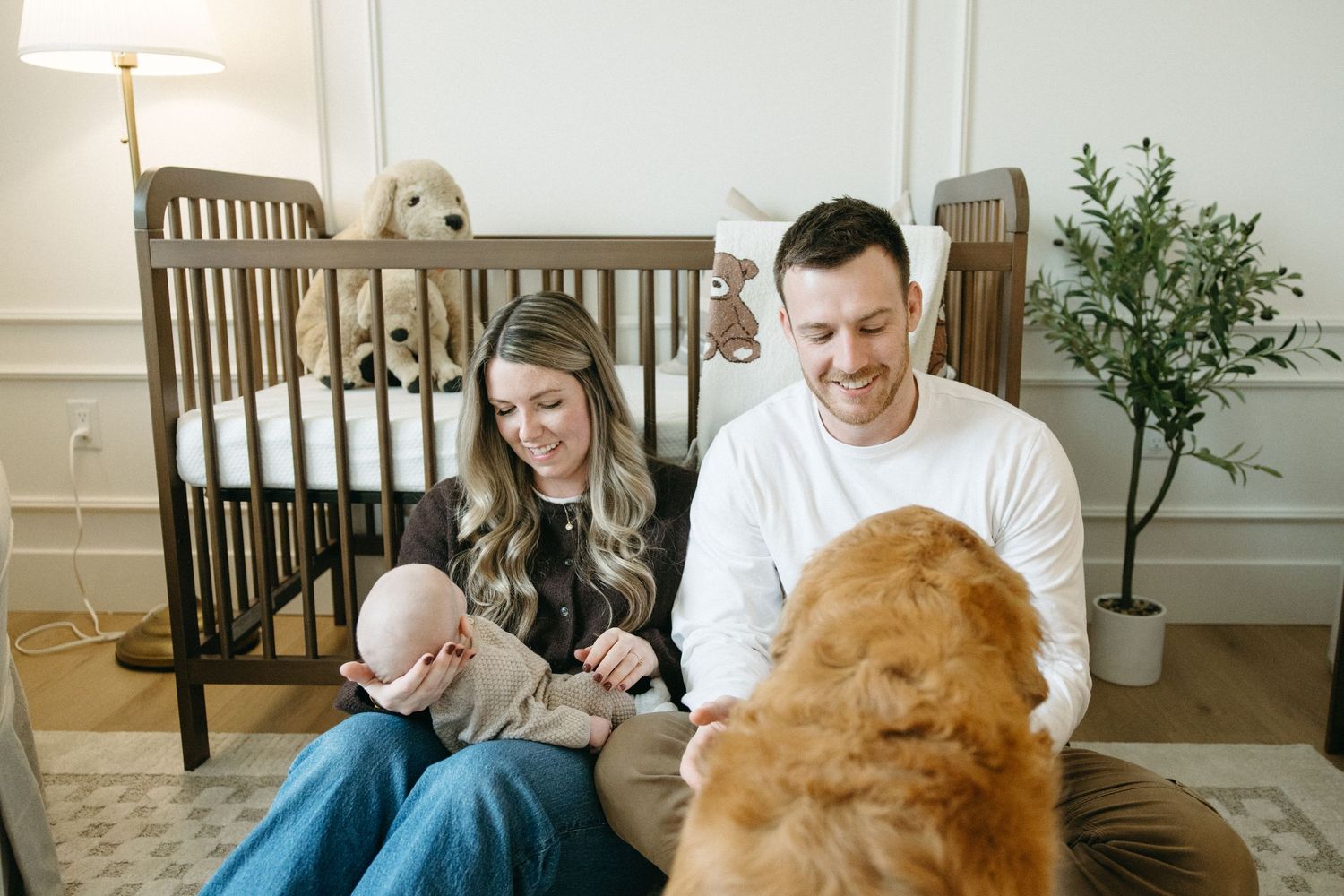 Family bonding time in bright nursery with dog and baby.