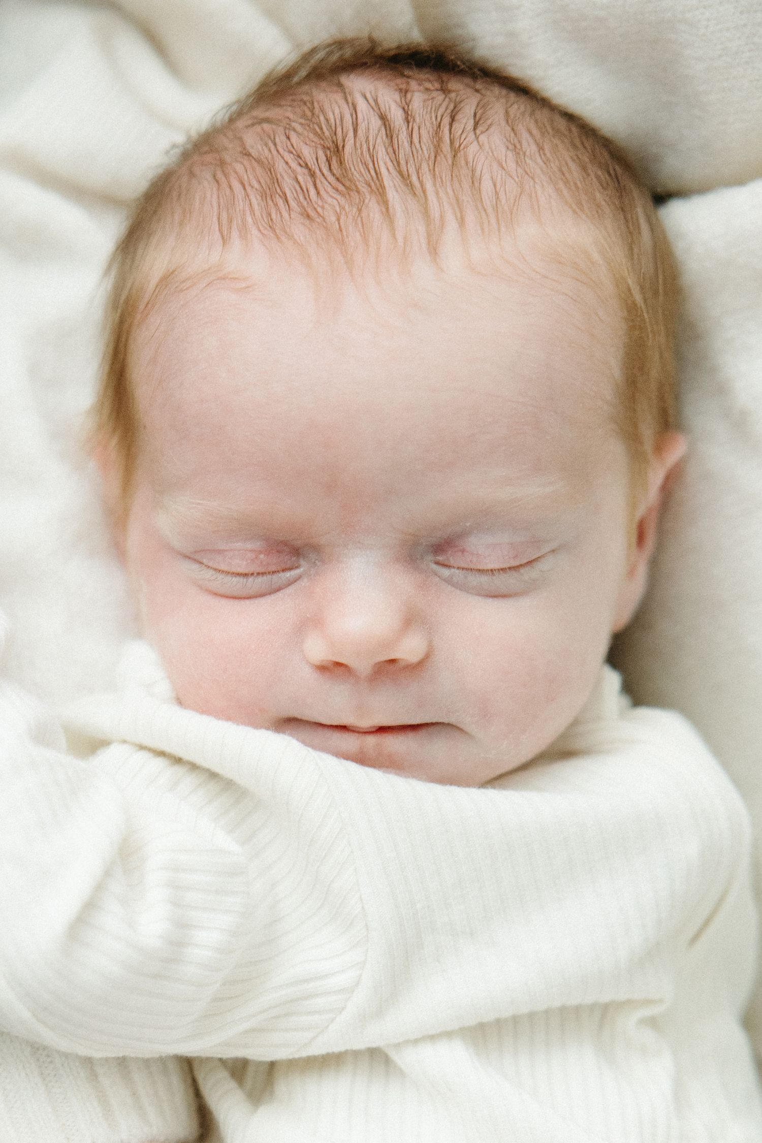 Peaceful sleeping newborn baby wrapped in soft white blankets showing different angles of their serene face.