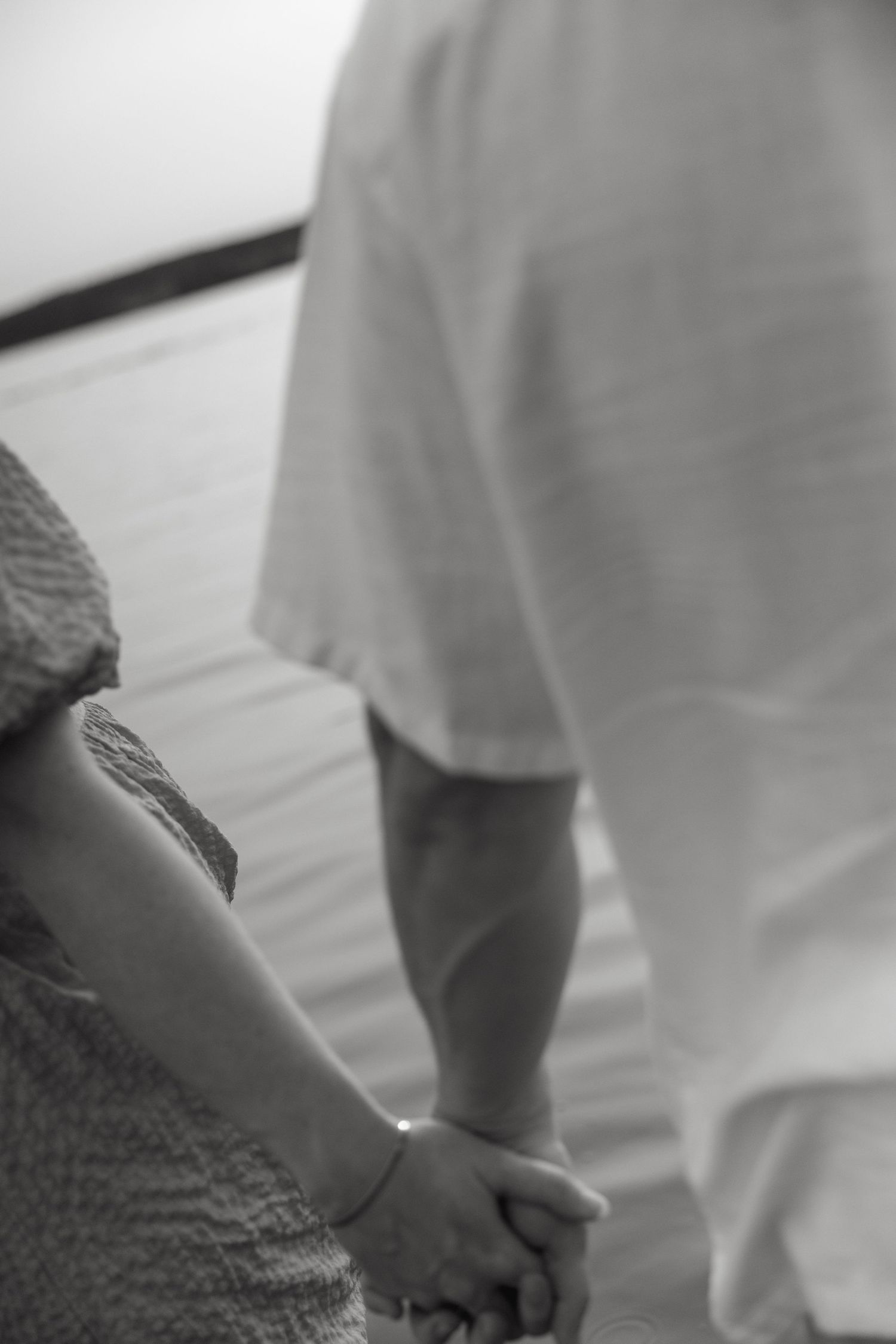 Close-up black and white image of two people holding hands tenderly.