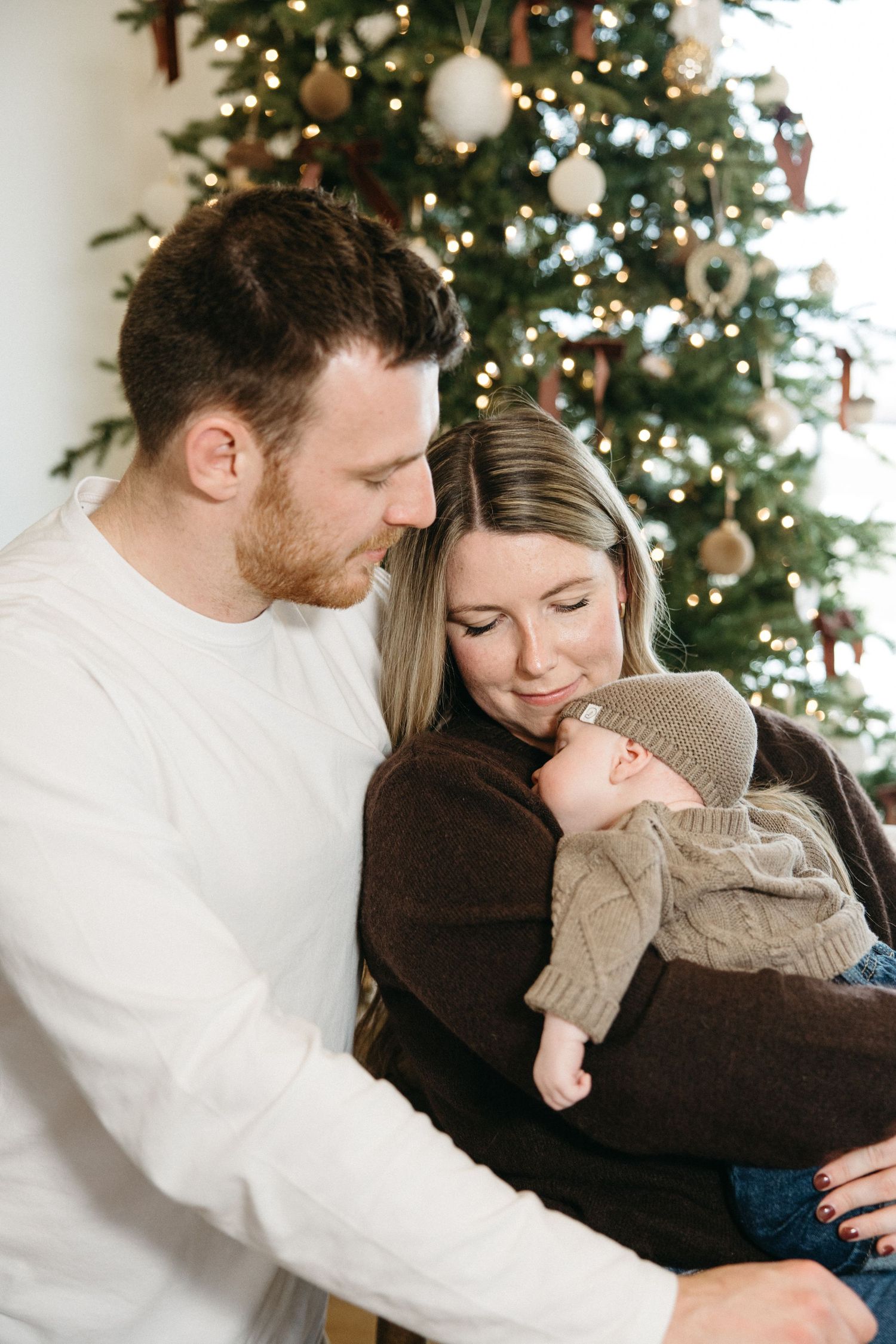 Intimate family moments captured in front of a decorated Christmas tree.