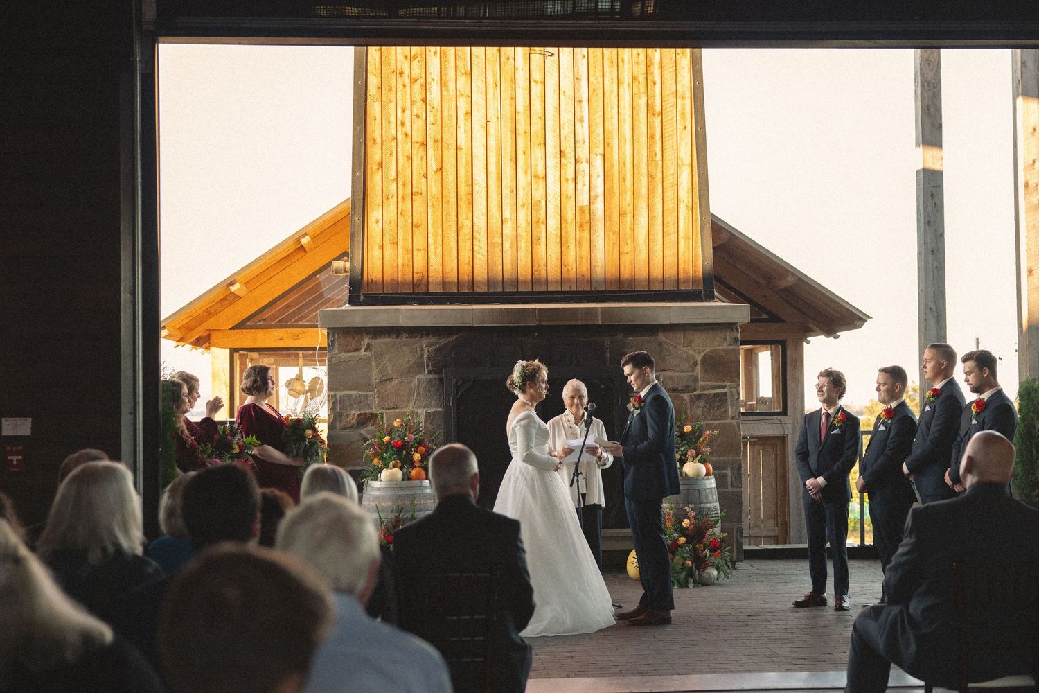 Wedding ceremony in a rustic wooden venue with warm lighting and gathered guests.