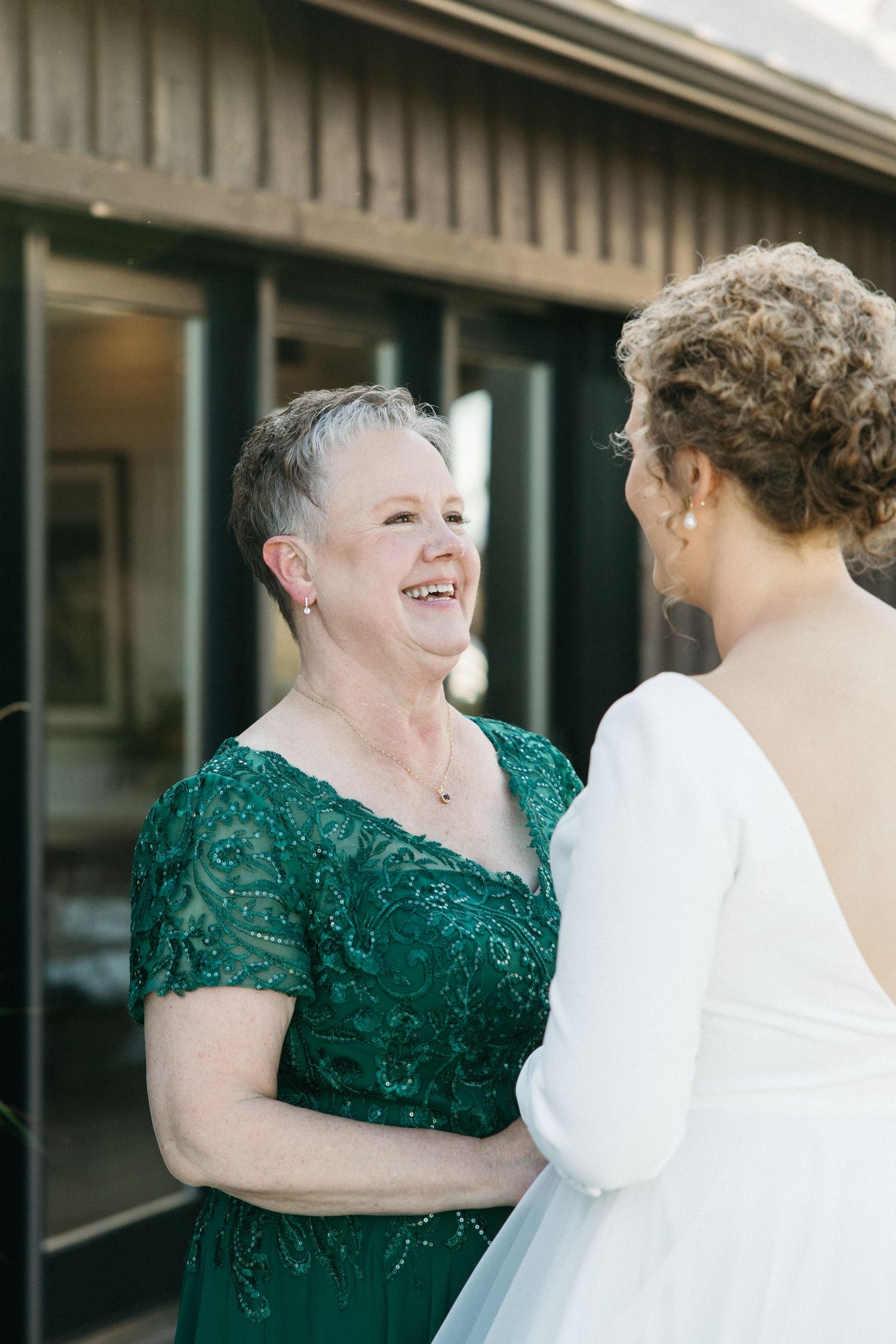 Two people sharing a joyful moment outdoors wearing formal attire.