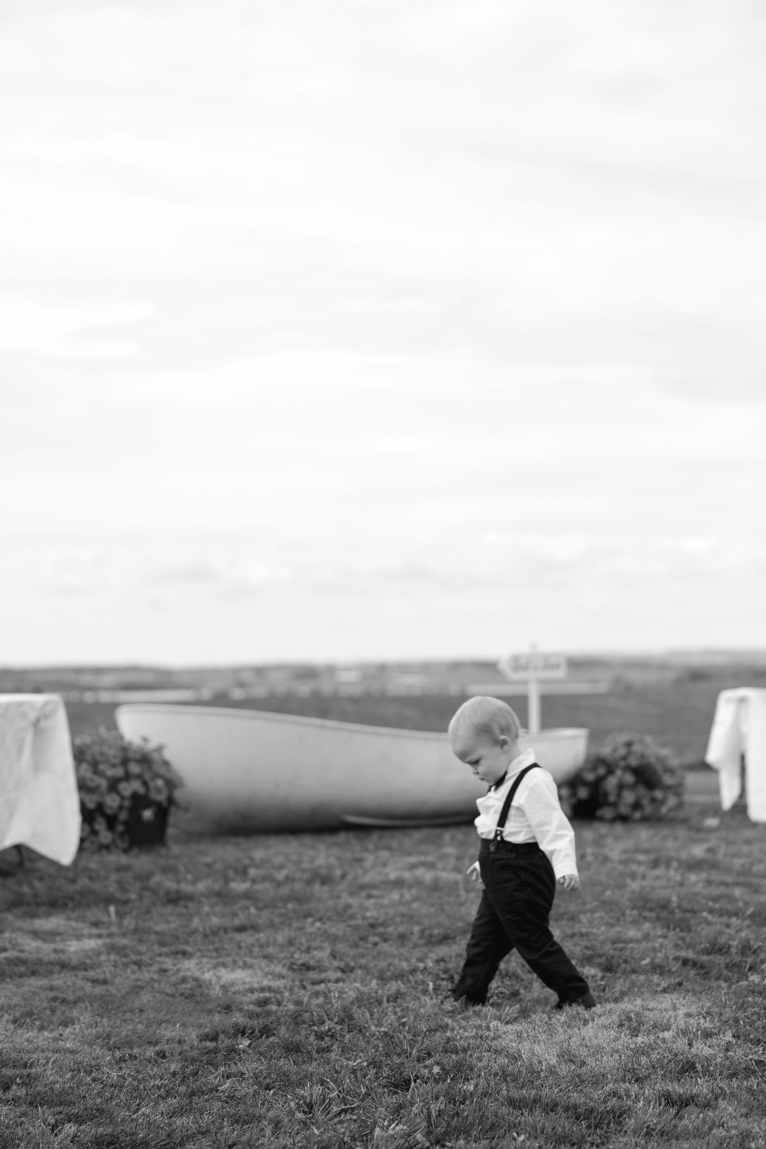 Black and white sequence of small figures walking across a grassy field.