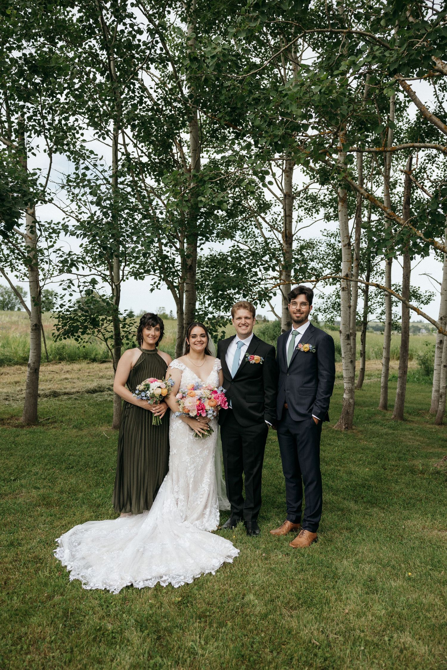Formal wedding party portrait in a grove of birch trees on grassy hillside.