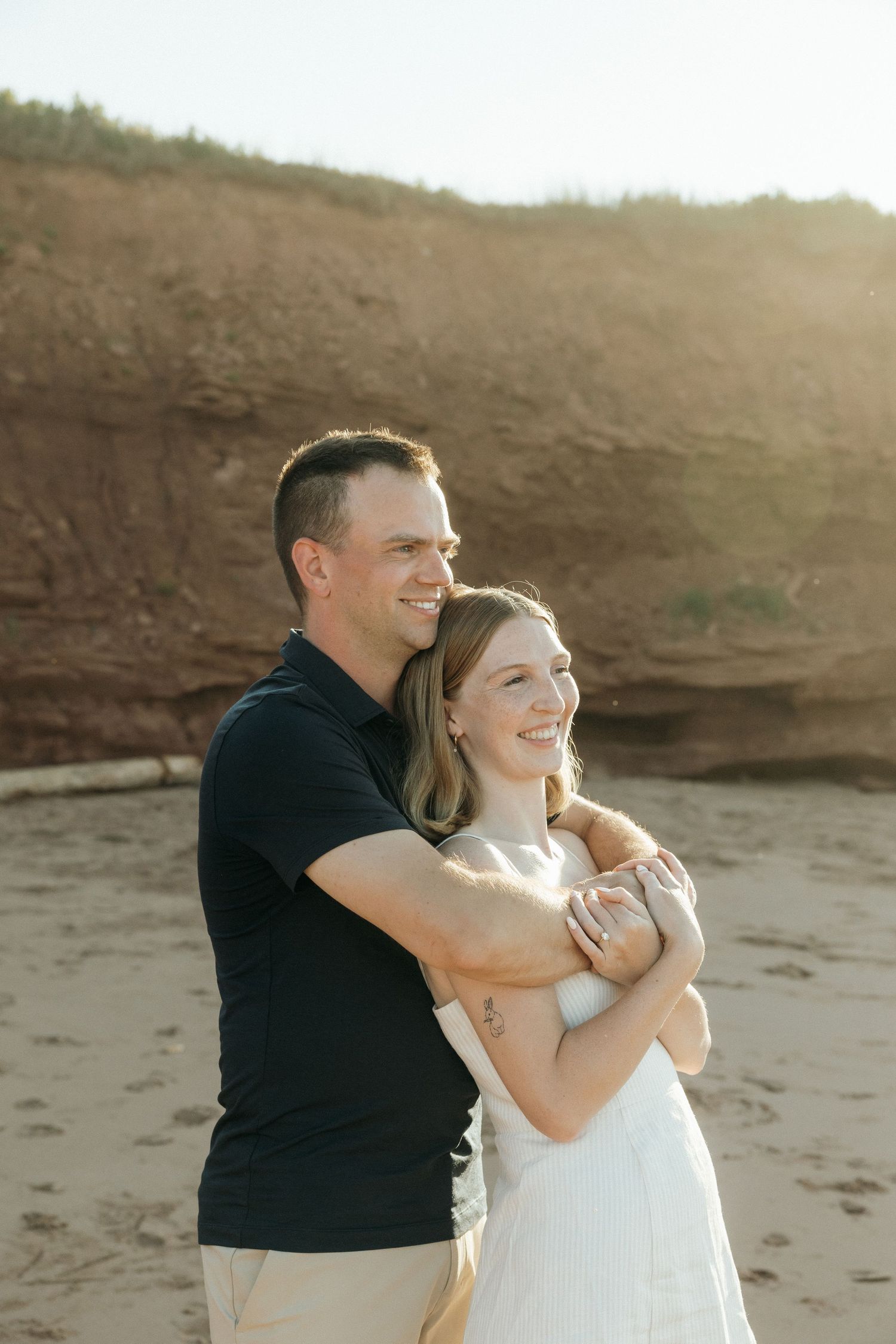 A joyful moment captured between two people on a beach with cliffs in the background.