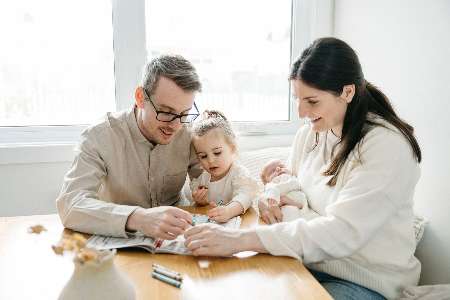 Family spending quality time together drawing and coloring at a white table in a bright room.