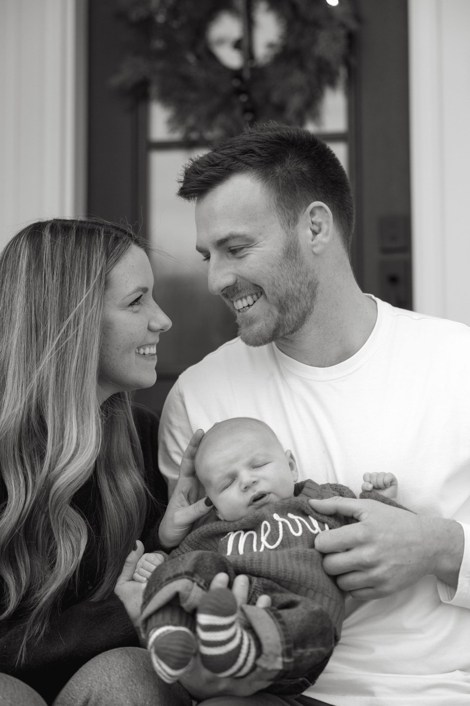 Sweet family moments shared with a baby in front of a decorated holiday setting.
