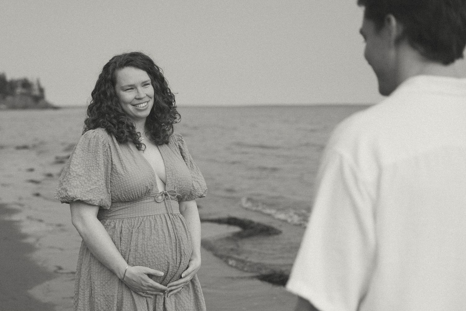 Couple sharing tender moments on a beach during a black and white photoshoot.