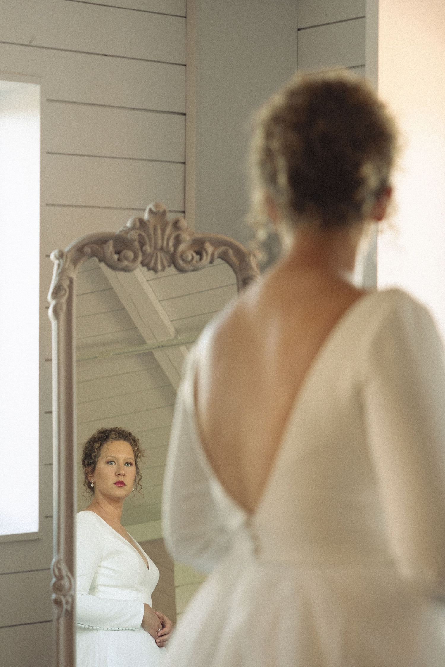 Reflection of a white dress in an ornate vintage mirror.