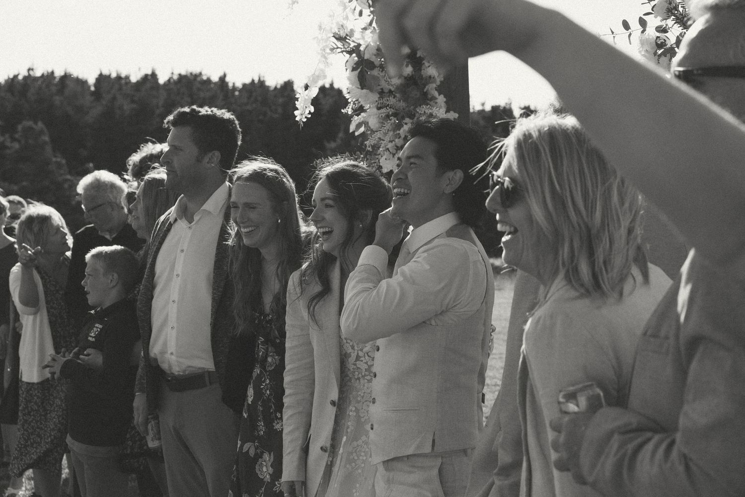 Black and white photo of wedding guests gathered outdoors for ceremony.