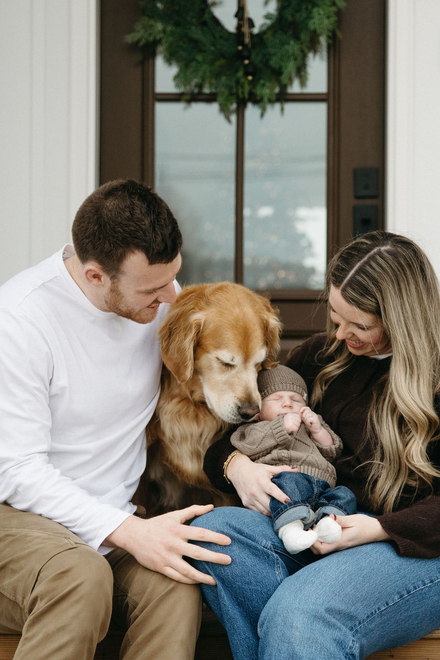 Family and golden retriever sharing intimate moment on brown couch during holiday season.