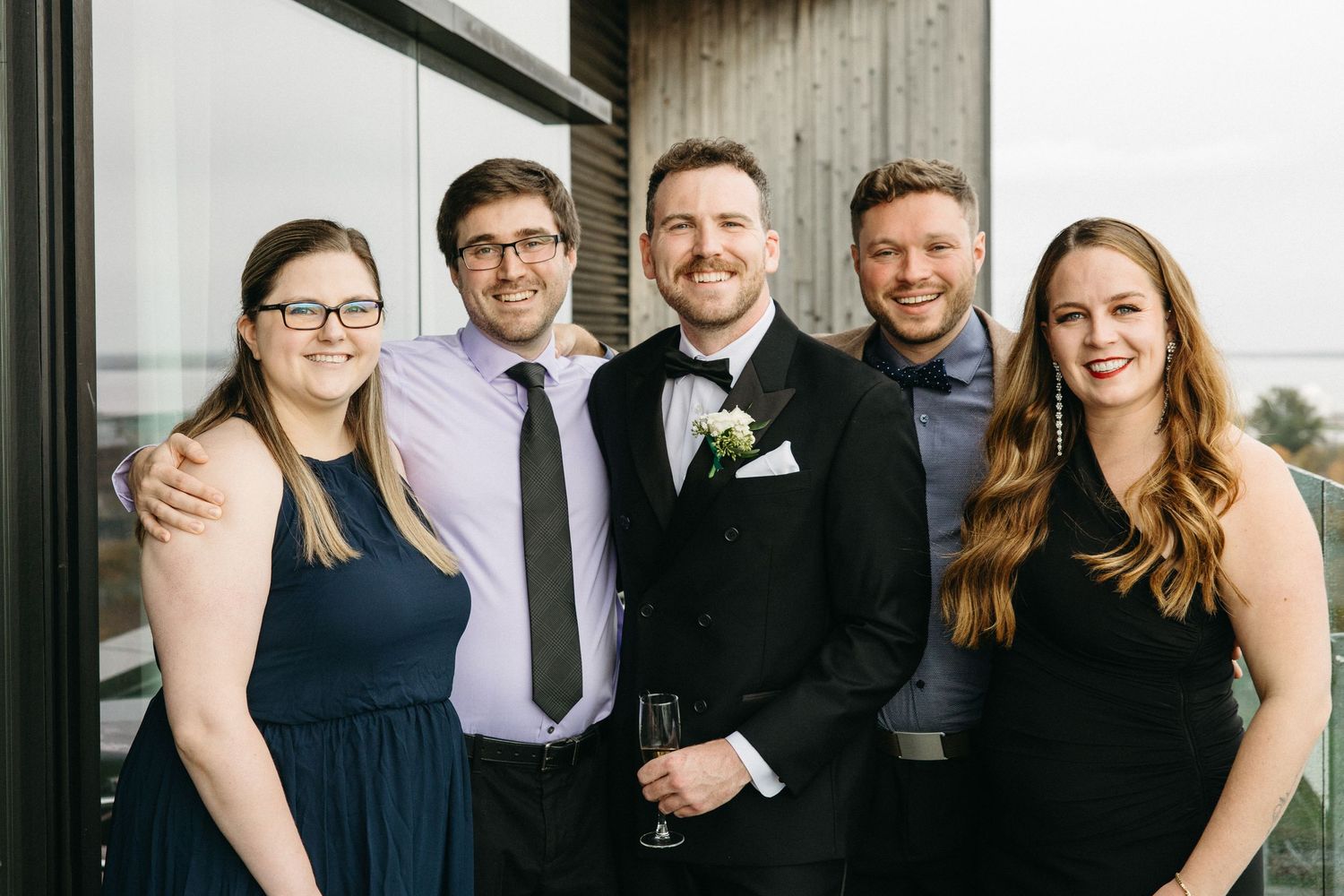 A formal gathering of people posing together on a modern balcony.