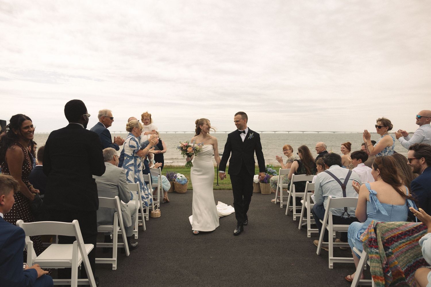 Bride and groom walk back down the aisle after ceremony at stunning waterfront outdoor wedding venue.