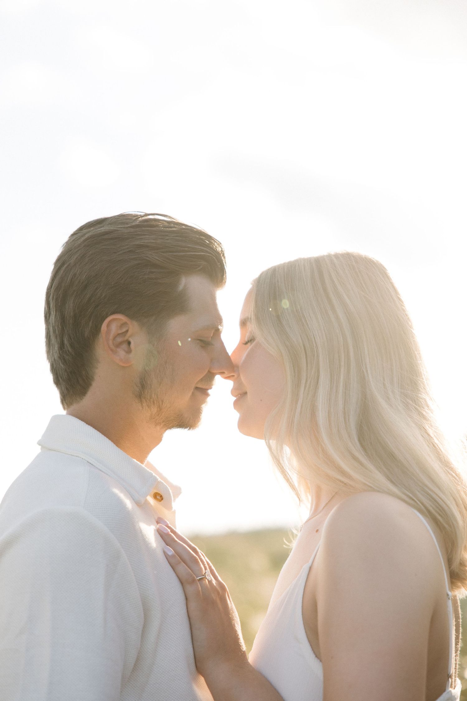 Couple sharing romantic almost-kiss moment backlit by golden sunlight.